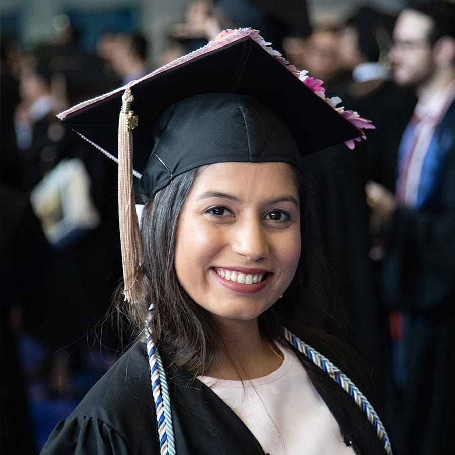 Smiling girl at graduation in cap & gown.