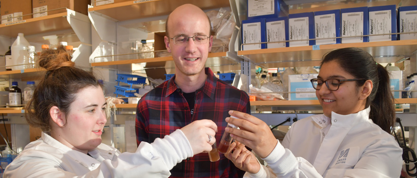 Science faculty member teaching 2 female undergraduate students chemisry