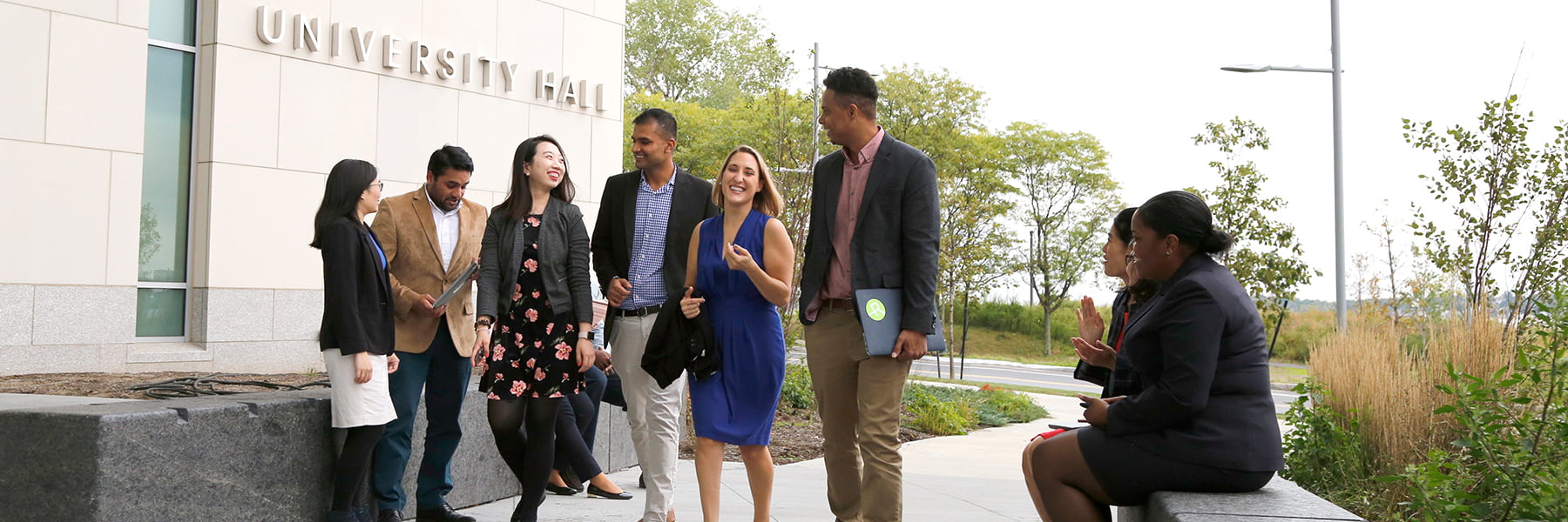 Business students walk and talk outside of University Hall.