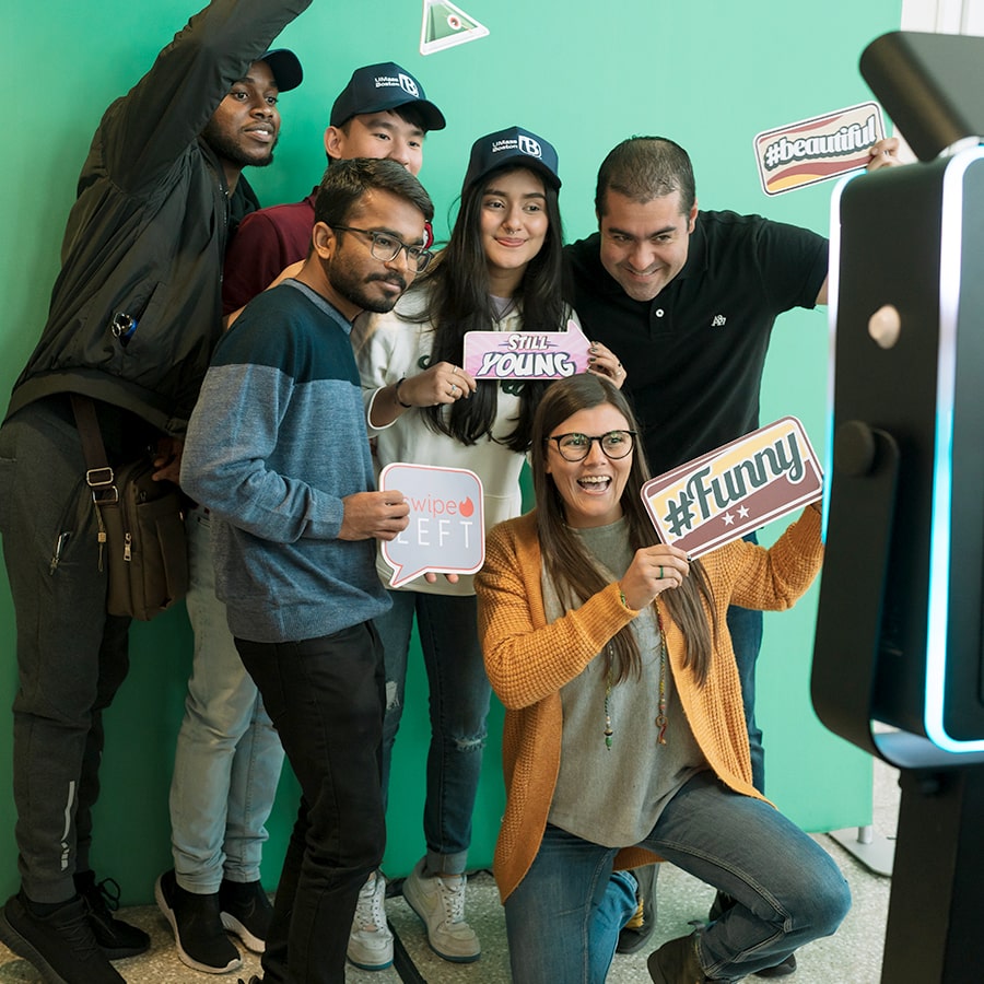 Group of students poses at the photo backdrop holding up hashtag signs.