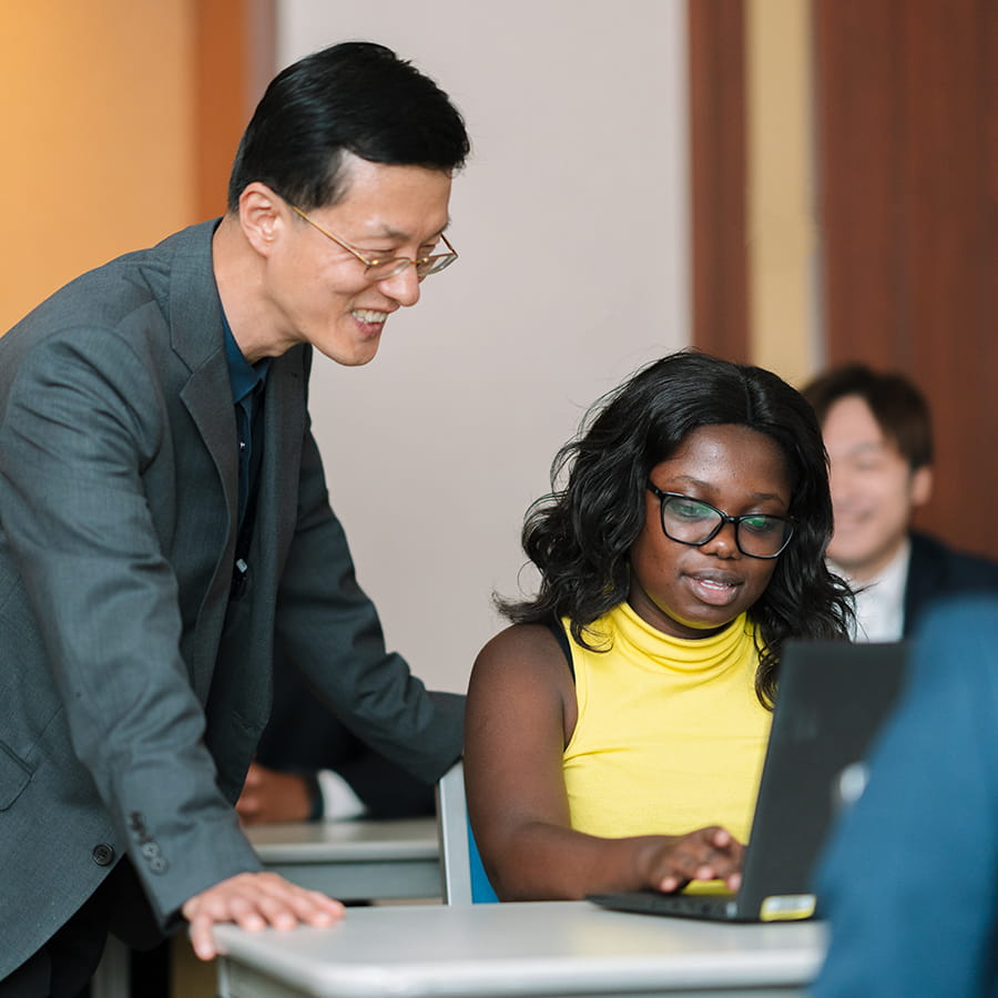 Teaching and student looking over laptop.
