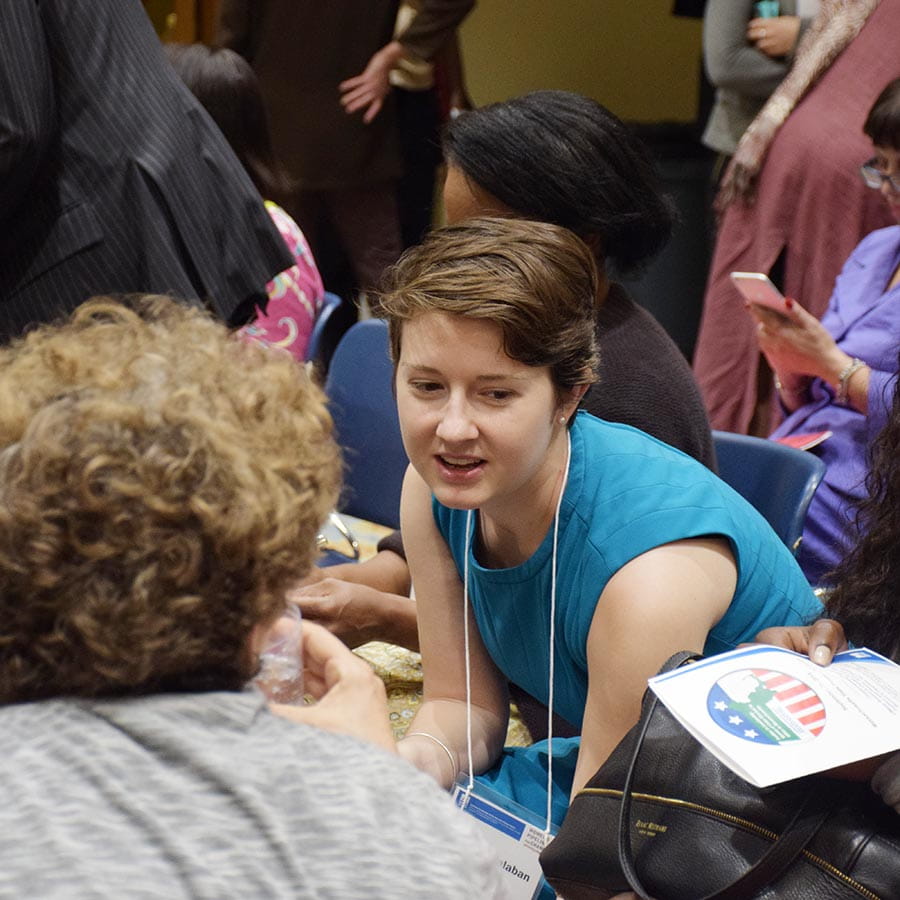 woman leans over to connect with another conference attendee