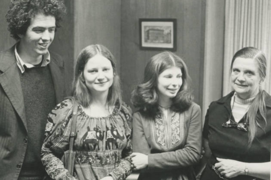 A black and white photo of four students posing and smiling