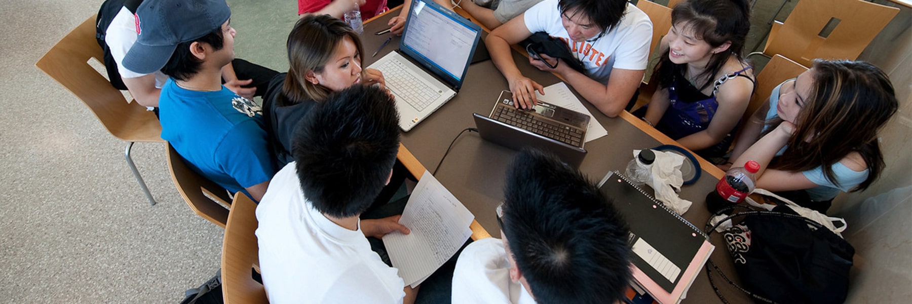 Students study together on laptops at table campus center dining hall.