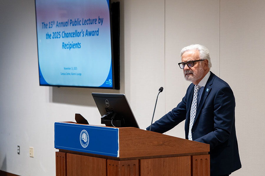 UMass Boston Chancellor Marcelo Suárez-Orozco stands at a podium, giving an introduction.