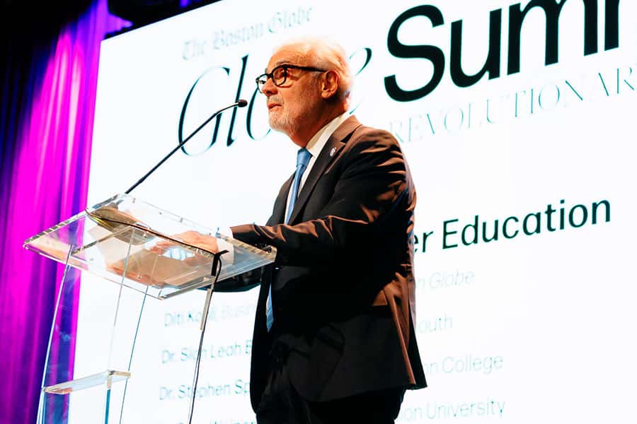 UMass Boston Chancellor Marcelo Suárez-Orozco stands at a podium at the Globe Summit, giving an introduction.