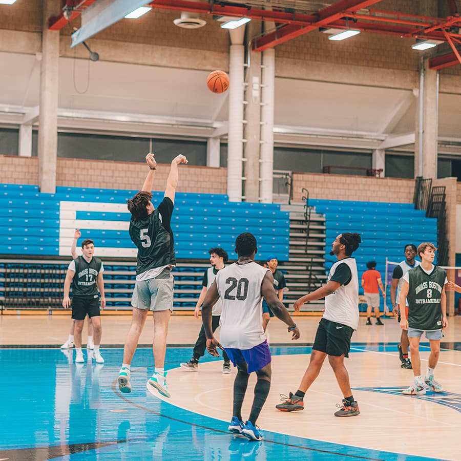 Students play basketball inside gym.