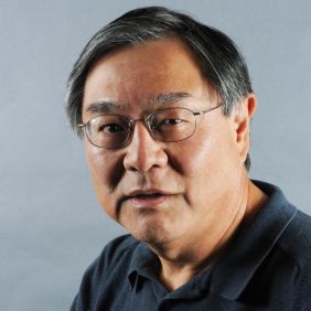 Man in black polo with metal frame glasses against grey background
