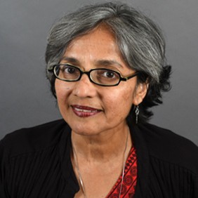 Woman with short grey and black hair, black glasses, red shirt, and black cardigan